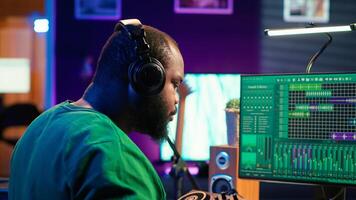 Confident music engineer working on mixing console in home studio, producing new sounds for a song and editing volume levels in daw software. Audio technician recording acoustic files. Camera A. photo