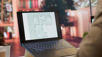 Businessman searching for commercial office spaces from his home workstation, doing a blueprints review and drafting building layouts to find the perfect startup property. Real estate. Camera A. photo