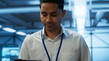 System administrator in data center managing and maintaining databases, ensuring data integrity, security and availability. IT worker updating server room supercomputers systems, camera A photo