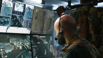 Army telecommunication systems operator using radio and satellite equipment. Middle Eastern military dispatcher managing communications networks, looking at screens, camera A photo