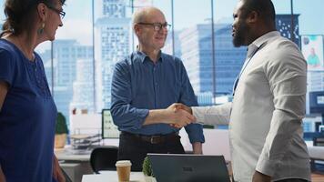 Senior people consulting financial advisor about retirement and pension planning, shaking hands for securing the future with life insurance and savings. Financial options in modern office. Camera B. photo