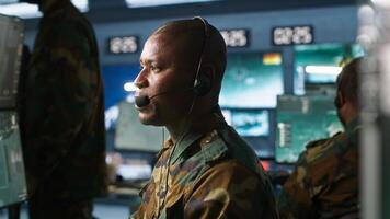 Army telecommunication systems operator using radio gear, providing combat support, doing patriotic duty. African american military dispatcher managing communications networks, camera A photo