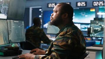 Army operative in command center analyzing surveillance data during global warfare. Intelligence agent in base of operations completes mission during World War 3 geopolitical operation, camera A photo