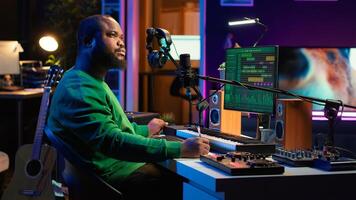 Composer writes verses and ideas to develop original song in home studio before recording new audio files. Songwriter using musical equipment and his imagination, artist composes music. Camera A. photo