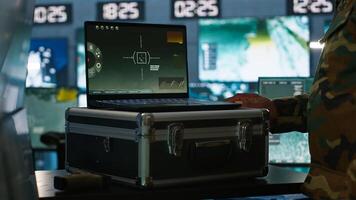 Air force officer performing tactical level surveillance in command room using laptop. Close up of military specialist in base of operations using radar on notebook to look at assault zones, camera A photo