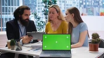 Financial advisor presenting financial guide to customers using green screen laptop. Agent in office assisting clients with investment portfolio management helped by chroma key notebook, camera A photo
