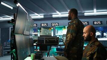 Military soldier wearing camo uniform in mission control center, overseeing national safety operations using laptop. Army expert examining data in monitoring room command center, camera B photo