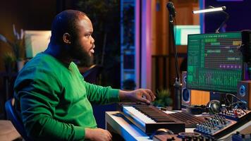 Sound engineer recording piano notes with DAW software in his home studio, working at night on producing new music with electronic tools. Musician composing tunes on midi controller. Camera A. photo