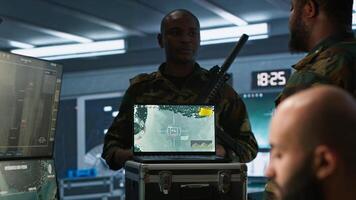 Military soldier wearing camo uniform in mission control center, overseeing national safety operations using laptop. Army expert examining data in monitoring room command center, camera A photo