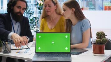 Financial advisor showing data graphs on green screen notebook to customers, analyzing market trends to do forecasting. Clients checking investment plan on chroma key laptop, camera A photo