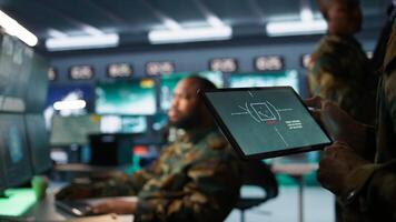 Military agent working in control room, using software on tablet, analyzing aerial reconnaissance data. Close up of intelligence corps expert controlling drones with portable device, camera B photo