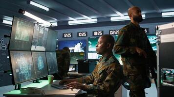 Army professional employing AI tech to improve military combat systems and missiles monitoring. African american IT admin uses neural networks to enhance combat operational capabilities, camera B photo