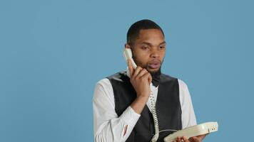 Bellboy concierge staff answering landline phone call to make reservations, discussing with clients about five star hotel rooms and amenities. Using telephone with cord to assist. Camera A. photo