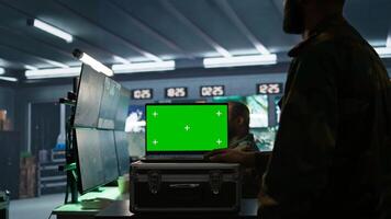 Soldier using tracking software on green screen laptop to gain info against enemies. Army expert using chroma key notebook to gain intel helping troops, coordinating mission activities, camera B photo