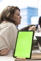 Employees and shareholders using chroma key screen in a corporate briefing, reviewing economic indicators on papers. Business people discussing finance planning and setting strategic goals. photo