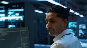 Portrait of smiling technician in data center implementing and managing infrastructure to ensure optimal performance and reliability. Happy IT specialist in server room coding on computer, camera A photo