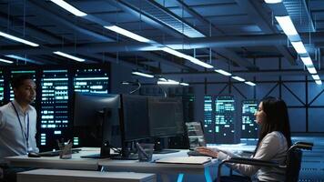 Person with paraplegia in inclusive server hub overseeing data center, making improvements. Woman in wheelchair doing tasks in data center, tracking network traffic, camera B photo