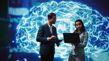 Coworkers using AI neural networks modeled after human brain, brainstorming ways to solve complex problems. IT department staff members using deep learning to look at data and complete tasks, camera B photo