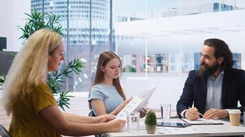 Financial adviser providing clients with informative leaflets on retirement planning, tax issues and wealth management. Agent in office assisting clients in setting up investment accounts, camera A photo