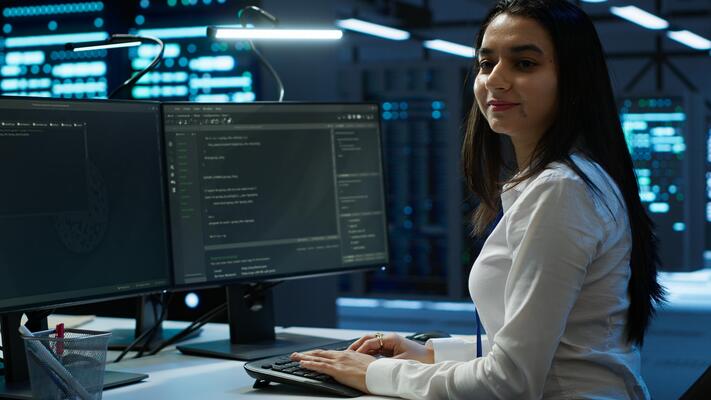 Portrait of smiling engineer overseeing data center, making improvements and updates to ensure system can handle networking tasks. Upbeat server room worker tracking network traffic, camera A