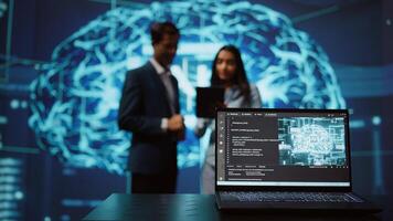 Focus on laptop in workspace used by AI researchers working with artificial intelligence in blurry background. Close up of notebook used by employees developing AI systems in tech startup, camera B photo