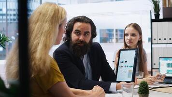 Financial advisor showing statistical graphs on tablet to clients, analyzing market trends to optimize their income. Mother and daughter checking investment plan on device, camera A photo