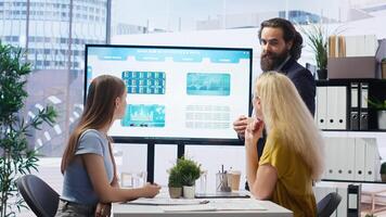 Financial adviser presents market analytics to customers using large display, explore best practices for building portfolio. Broker agent showing stock exchange charts to mother and daughter, camera B photo