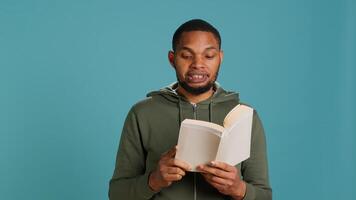 Man reading book aloud, narrating story for audience. Person enjoying literature novel, reciting from pages, entertaining spectators, isolated over studio background, camera A photo