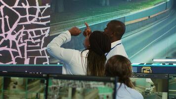 African american team monitoring routes and directions on satellite map, guiding delivery trucks to avoid traffic and ship orders faster. Operators consulting radar surveillance system. Camera A. photo