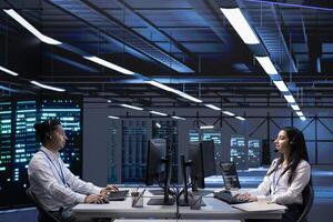 Teamworking technicians in data center call center responsible for providing logistics support to startups. Colleagues in server farm overseeing equipment systems and communicating with engineers photo
