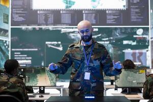 Military personnel studying a projection on hologram in command post, working on new defense operation plan. Soldier looking at real time CCTV satellite data on a holographic visualization. photo