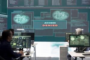 Displeased irritated team of hackers with denied access message on a big screen in governmental operations agency. Experts struggling to break into databases and steal server information. photo