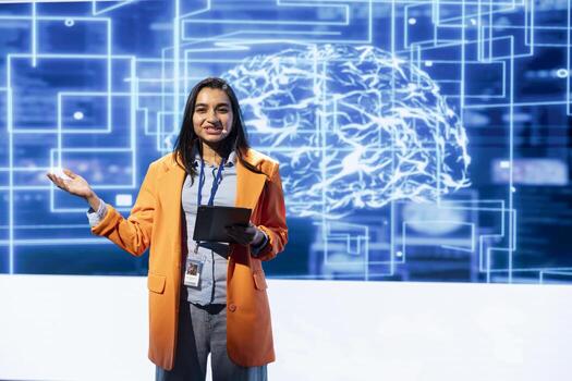 Cheerful engineer holding presentation at AI tech summit event gathering professionals using tablet. Jolly speaker using device to present how can AI be leveraged to accelerate innovation photo