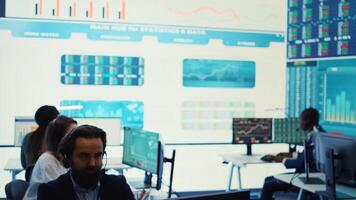 Team of forecast affiliates examining annual infographics on a big data screen, using workflow statistics at workstations. Diverse corporation employees reviewing latest budgeting plans. Camera B. photo
