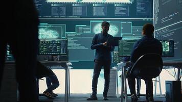 Group of governmental hackers analyzing digital threats on pc networks, using a big screen. Specialists working on collecting information, fighting against cybercrime and cyberterrorism. Camera B. photo