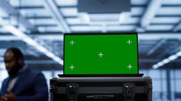 Green screen laptop used by engineers monitoring server room, doing checkup. Focus on chroma key notebook used by IT support employee working in data center facility, camera A close up photo
