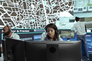 Call center operator transmitting parcel gps coordinates to customers, handling any order delay complains in agency control center. Employee monitoring truck drivers stuck in traffic, CCTV system. photo