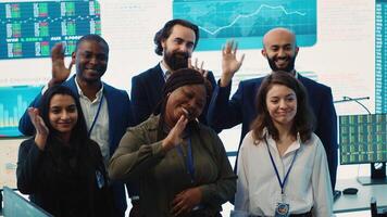 Confident smiling enterprise team uniting their forces to improve workflow and efficiency, achieve organizational goals. Diverse group of analysts work in telecommunications control room. Camera A. photo