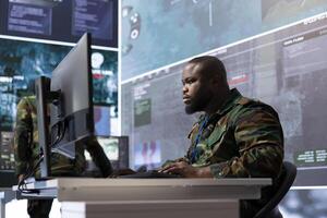 Military expert in an advanced operations center oversees satellite intelligence, managing surveillance systems on computer. Interpreting data to ensure national defense and strategic decisions. photo