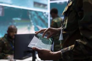 Army intelligence specialists using advanced computer systems and satellite data to enhance national security, critical information. Soldiers planning for a mission in high tech military control room. photo