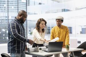 Realtor expert guides clients through a professional office tour, evaluating investment opportunity after reviewing the layout and blueprints of a high class urban building workspace. photo