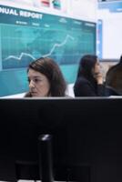 Marketing specialist studying infographics on computer in a monitoring room with big screen, check customer satisfaction from annual data reports. Employee review performance metrics. photo