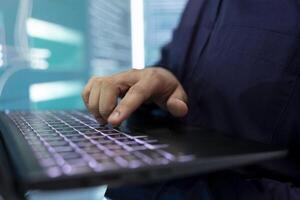 Hacker engaging in governmental espionage and using phishing techniques for illegal access to data, working on laptop in front of big screen. Spyware agency gains access into database. Close up. photo