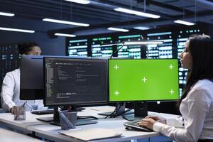 Specialists using green screen PC to check server clusters configuration settings. Engineers checking event logs in monitoring software to find faulty data center hardware root cause photo