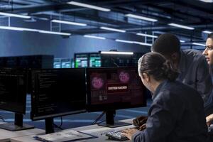 Multiethnic team of developers in server hub frightened by hacker passing firewall and stealing data. Diverse coworkers panicking after seeing security breach notification on monitor in data center photo