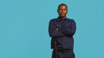 Portrait of smiling security agent securing assigned post, isolated against studio background. African american guardian prepared to handle security breaches and diffuse tense situations, camera B photo