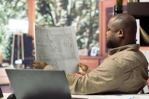 Professional businessman using digital tools to evaluate office blueprints, focusing on relocating to a modern and creative workspace. Developing an investment strategy for real estate. photo