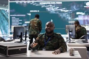 Professional military officer participates in a secure call online, leveraging high tech computer systems in modern operation room to coordinate intelligence and mission planning for defense. photo