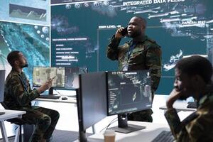 Group of soldiers in a high tech office environment collaborates on intelligence analysis, data processing and strategic planning. Maintaining national security and operational command service. photo