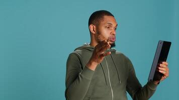 Man having entertaining conversation with friends during videoconference meeting using tablet, studio background. Person interacting with mates during internet videocall on portable device, camera A photo